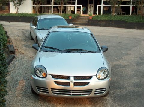1998 Ford Taurus - Two silver sedans parked in a gravel driveway in front of a house.