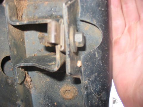 1988 Ford Bronco - This is a close-up view of a rusty metal bracket and bolt assembly on a vehicle's frame.