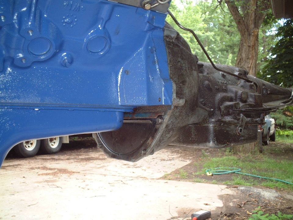 Blue engine block joined to a black transmission bellhousing outdoors