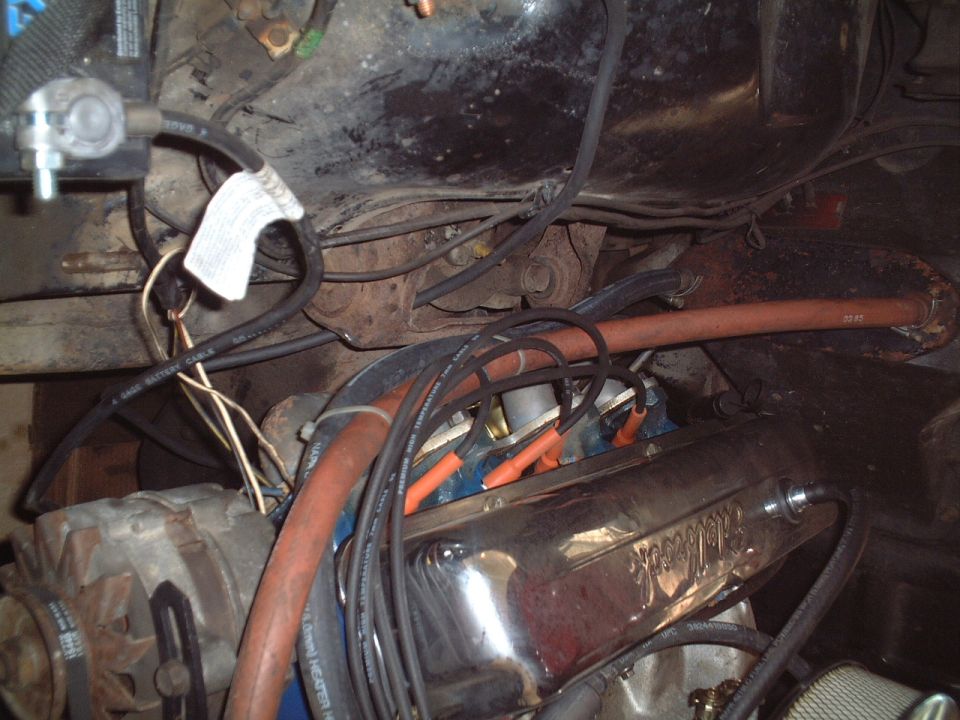 Engine bay with chrome Edelbrock part, orange plug wires, red hose and black cables