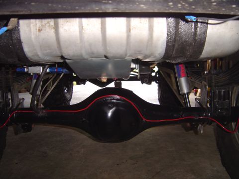 1978 Ford Bronco - Underside view of a vehicle's rear axle and fuel tank assembly.