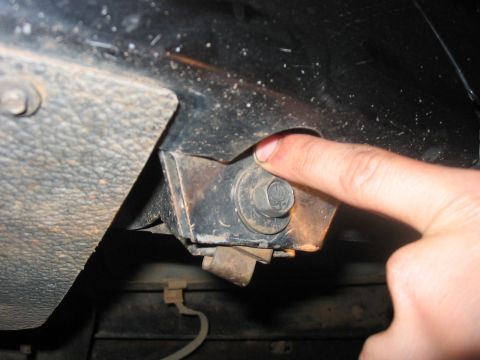 1988 Ford Bronco - A finger points to a bolt on a vehicle's frame, likely related to a slider attachment point.
