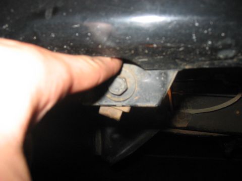 1988 Ford Bronco - A close-up view shows a bolt and bracket, with a finger indicating the fastener.
