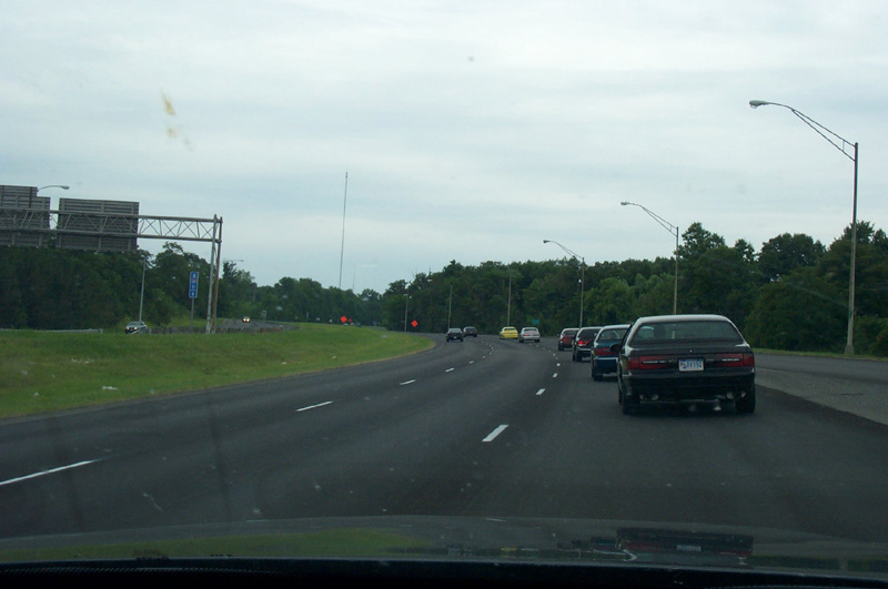 Windshield view of highway traffic with dark sedan ahead in right lane