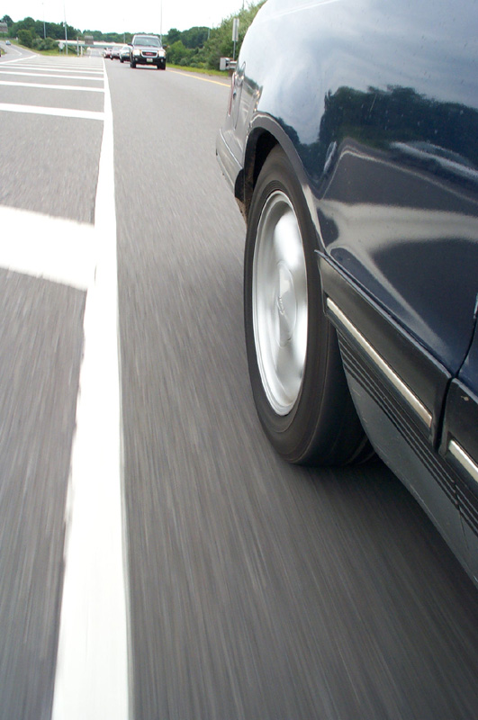 Low rolling shot of dark blue sedan front alloy wheel and chrome rocker trim
