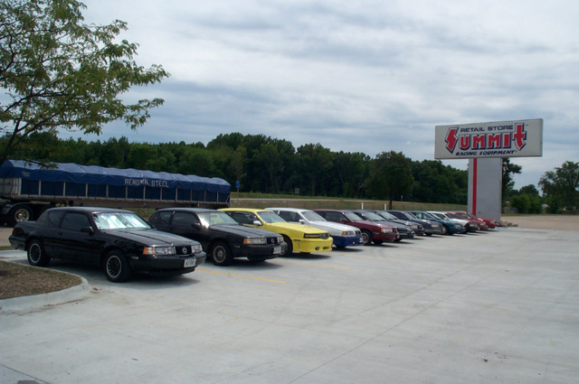 Twelve Thunderbird and Cougar coupes parked in a row outside a Summit Racing retail store