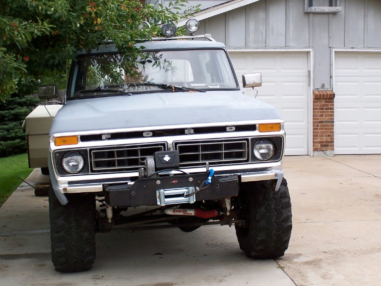 Front of lifted light-blue Ford truck with winch and roof lights on driveway
