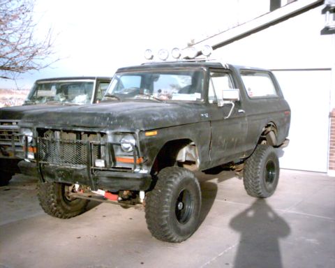 1978 Ford Bronco - A black 1978 Ford Bronco is parked in front of a garage, with another vehicle partially visible behind it.