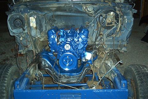 1986 Ford Bronco - The engine bay of a vehicle is shown with a blue-painted engine and frame components, indicating a rebuild or restoration in progress.