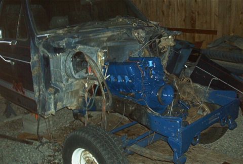 1986 Ford Bronco - Disassembled truck chassis with a freshly painted blue engine, undergoing repairs.