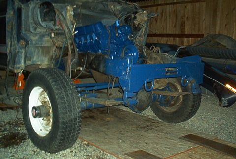 1986 Ford Bronco - Vehicle chassis with a freshly painted blue engine, undergoing repairs or rebuild.