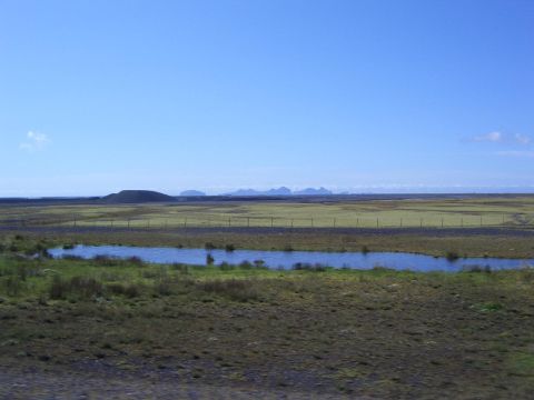 1996 Ford Bronco - Expansive rural landscape a small pond and distant hills under a clear blue sky.