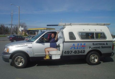 1988 Ford Bronco - A man sits on a toilet in the driver's seat of a pickup truck, waving to the camera.