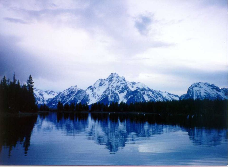 Mountain range reflected in a calm lake under a cloudy sky
