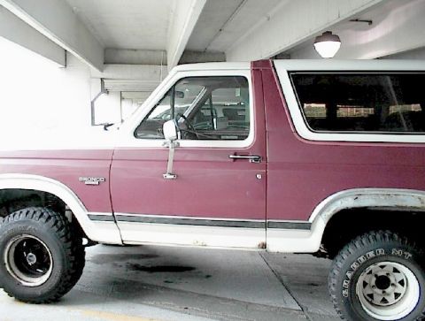1984 Ford Bronco - The side profile of a two-tone Ford Bronco shows its classic body style and off-road tires.