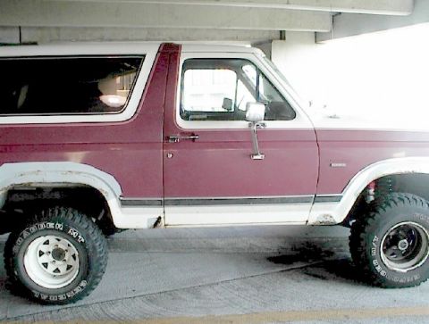 1984 Ford Bronco - This maroon and white Ford Bronco is shown from the side, aftermarket wheels and tires.