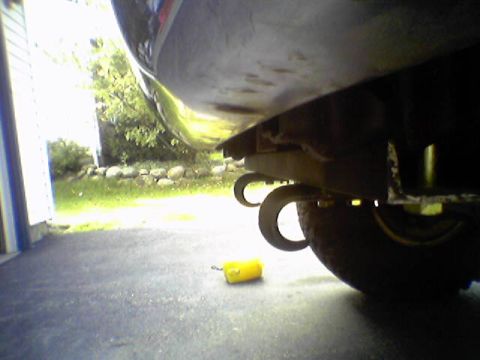 1993 Ford Bronco - The rear underside of a vehicle is visible, with two circular exhaust tips and a yellow object on the asphalt.