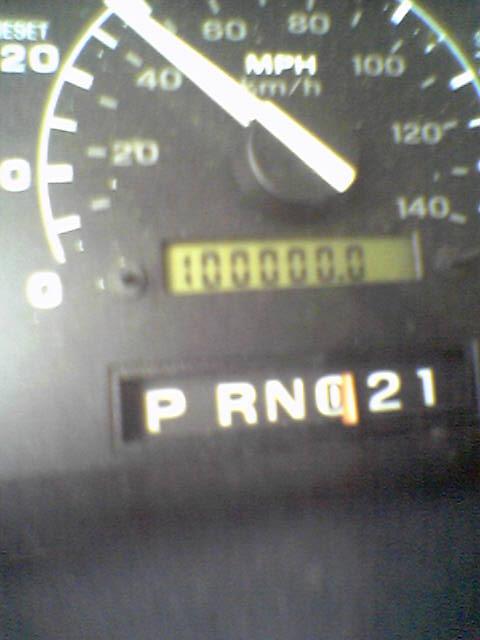 1993 Ford Bronco - Dashboard gauges display speed, mileage, and gear selection, indicating 100,000 miles on the odometer.
