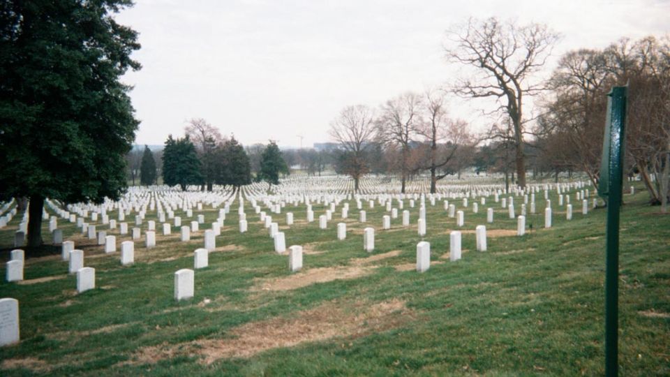 Arlington National Cemetery with rows of white headstones under a cloudy sky