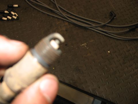 1988 Ford Bronco - A close-up of a spark plug, with spark plug wires visible in the background.