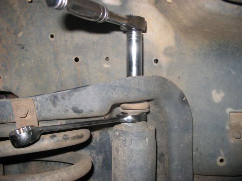 1988 Ford Bronco - A mechanic works on a vehicle's suspension system, focusing on a shock absorber and spring assembly.