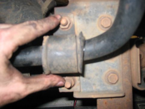 1988 Ford Bronco - Close-up of a sway bar mount with a finger indicating a bolt. The bracket appears rusty.