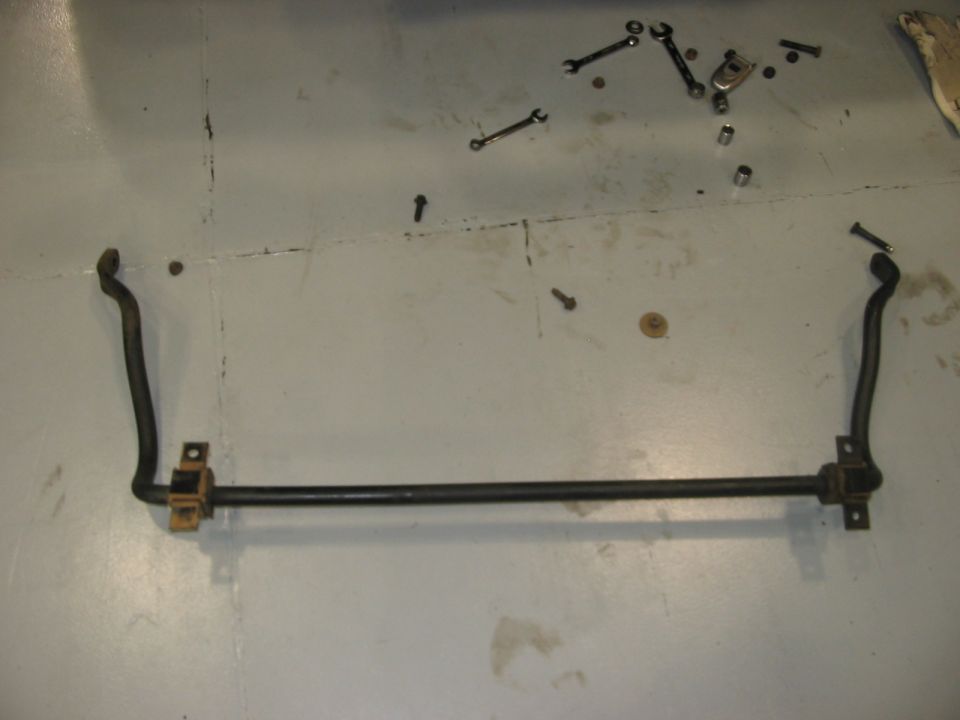 Sway bar with yellow bushings on a concrete floor with tools scattered around