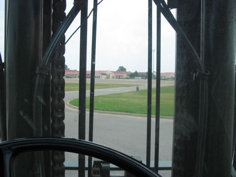 1988 Ford Bronco - Looking out through a fence at a road and some buildings under a cloudy sky.