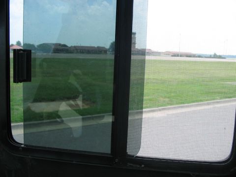 1988 Ford Bronco - Looking out the window of a vehicle at a grassy field and some buildings in the distance.
