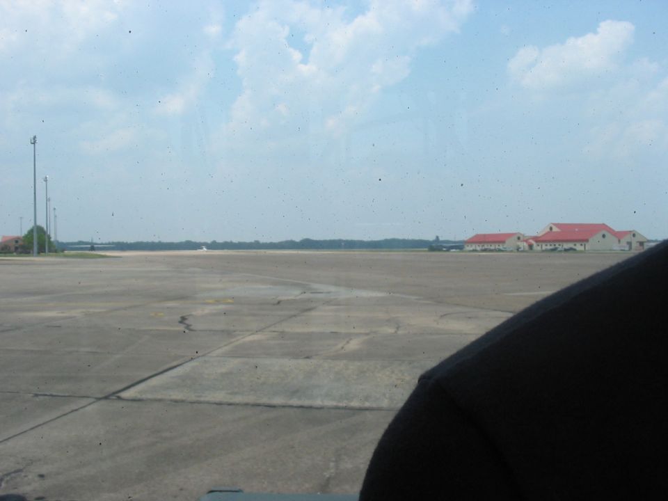 Interior view of a vehicle looking out at an airport tarmac with buildings in the distance
