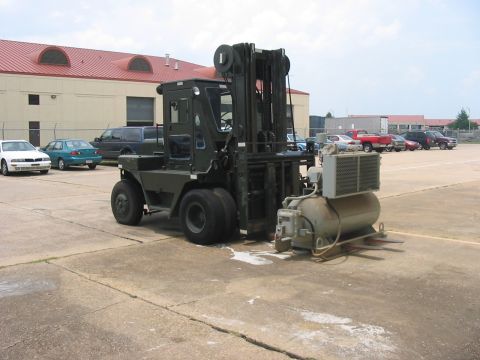 1988 Ford Bronco - A military-style forklift is parked next to a large air compressor unit.
