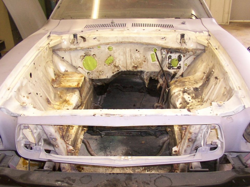 1978 Ford Mustang II engine bay, stripped down for restoration, showing rust and missing engine components