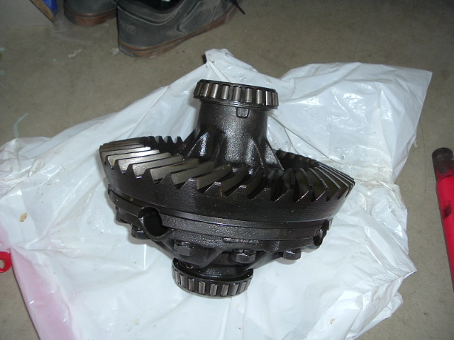 Differential carrier with ring gear on white plastic bag on concrete floor.