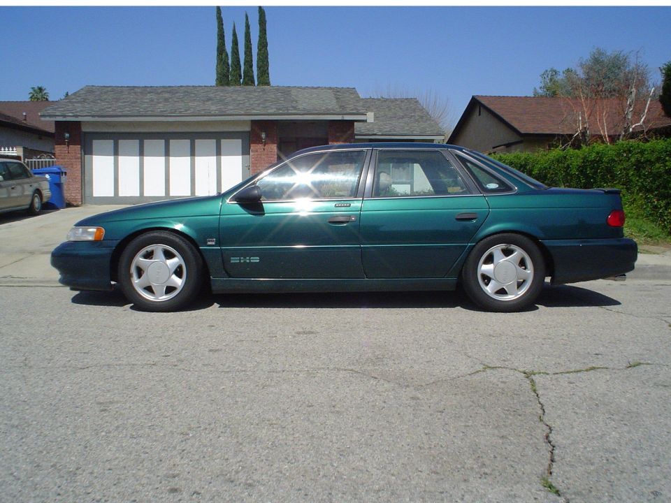 Green Ford Taurus SHO sedan side profile parked at a residential curb on a clear day