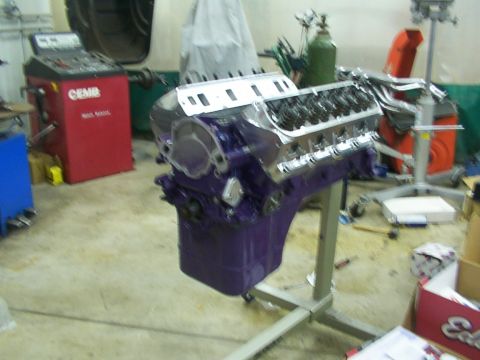 1978 Ford Mustang II - Engine block painted purple sits on a stand in a workshop, with various tools and equipment in the background.