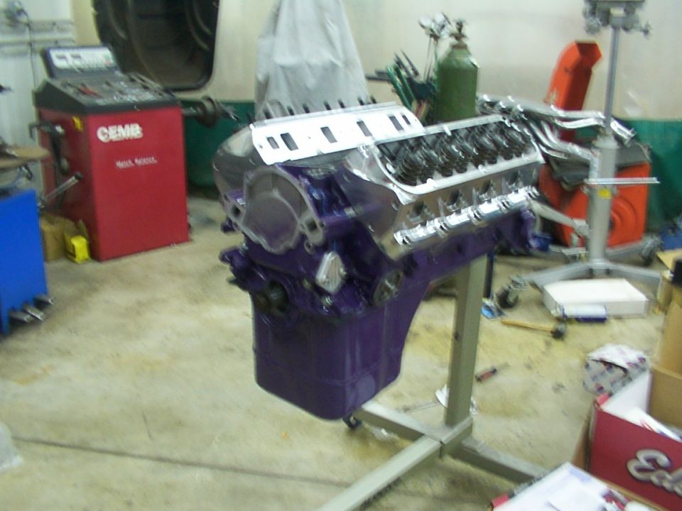 purple engine on stand in garage with tire balancer and other equipment