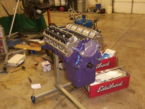 1978 Ford Mustang II - A purple engine is mounted on a stand in a garage, surrounded by parts and tools.