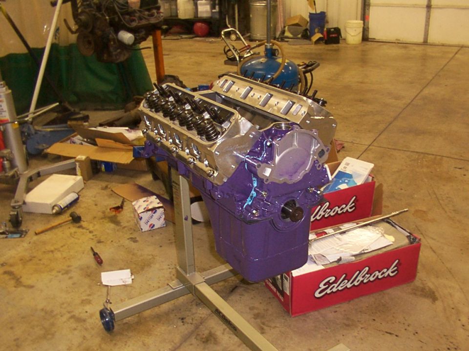 Purple engine block on a metal stand, with Edelbrock boxes nearby