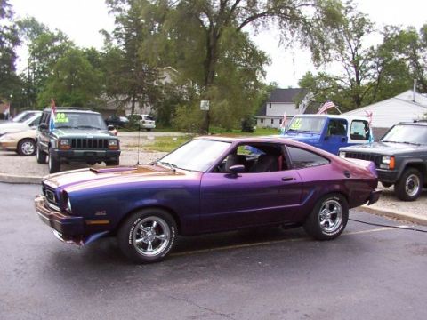 1978 Ford Mustang II - A custom painted coupe with chrome wheels is parked in a lot with other vehicles.