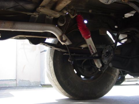 1996 Ford Bronco - Close-up of the rear suspension system, a red shock absorber and leaf springs.