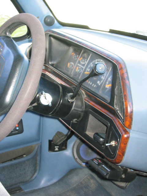 1989 Ford Bronco - Driver's side dashboard of a light blue truck interior shot from the passenger seat, showing the instrument cluster with speedometer and au…