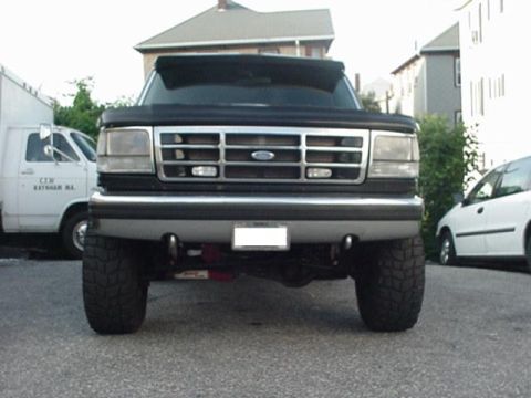 1993 Ford Bronco - This Ford F-Series truck has a prominent chrome grille and large tires, seen from a low front angle.