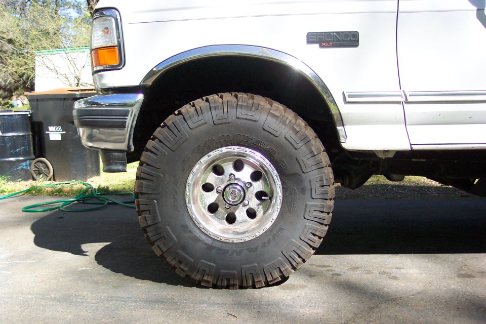 Goodyear Wrangler tire on polished aluminum wheel of white Ford Bronco XLT, close-up side view