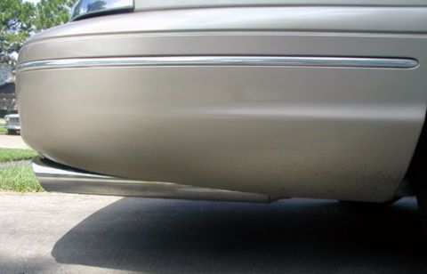 2000 Ford Crown Victoria - The rear quarter panel and exhaust pipe of a gold 2000 Ford Crown Victoria are visible.