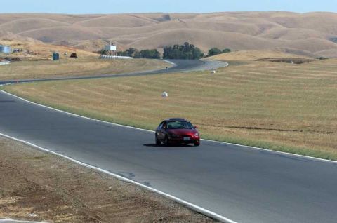 1997 Ford Taurus - A red sedan navigates a turn on a race track under a clear sky.