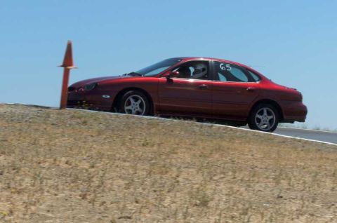1997 Ford Taurus - Red 1997 Ford Taurus sedan with racing number 65 on door, navigating a turn on a racetrack.