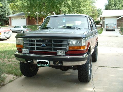 1994 Ford Bronco - Front view of a lifted 1994 Ford Bronco with off-road tires parked in a driveway.