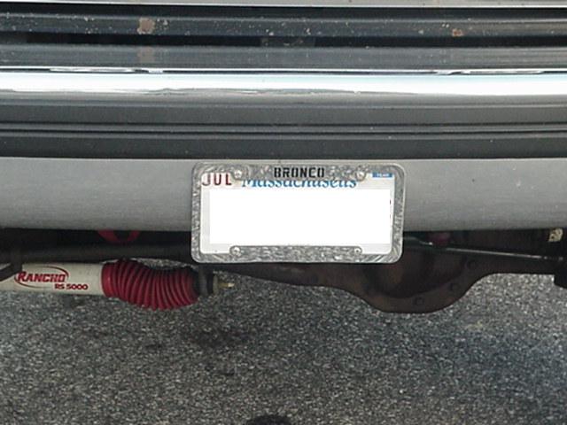 Rear view of a silver vehicle with a Massachusetts license plate that reads "BRONCO". A Rancho RS 5000 shock absorber is visible