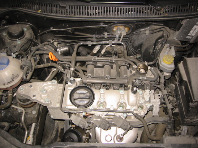 Bare four-cylinder VW engine with cover removed showing throttle body and injectors