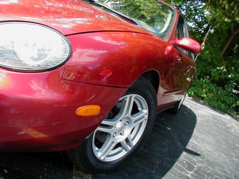 1997 Ford Taurus - Close-up of a red 1997 Ford Taurus showing the front fender and wheel.